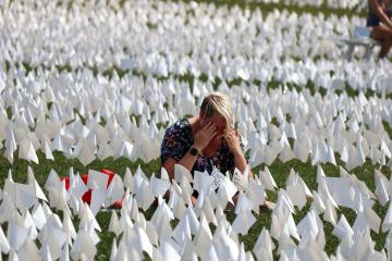 A woman kneels and cries in a field of white flags