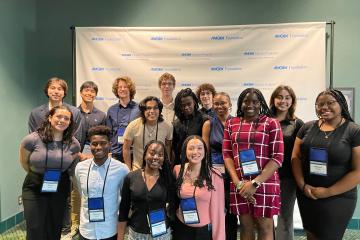 15 students smile for a group photo.