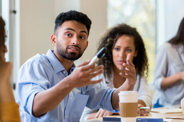 Man speaking confidently to co-workers gathered around a table.