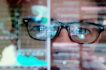 Closeup of a man concentrating on a touch screen display showing moving data
