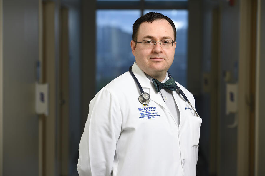 A professional photo of Eugene Shenderov wearing a doctor's coat, stethoscope, and bow tie.